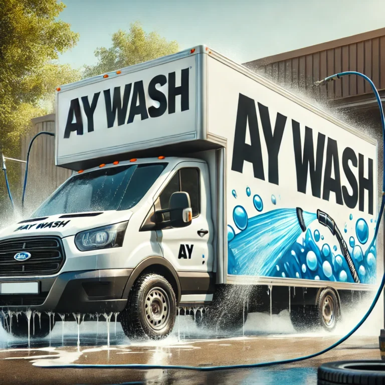 Camion de lavage de voiture mobile "Ay Wash" en train de laver une autre voiture avec de l'eau et des bulles de savon visibles, stationné dans un parking par une journée ensoleillée.
